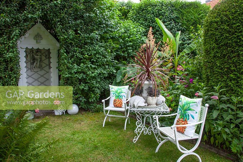 Seating area in the garden with Cordyline australis in a pot 