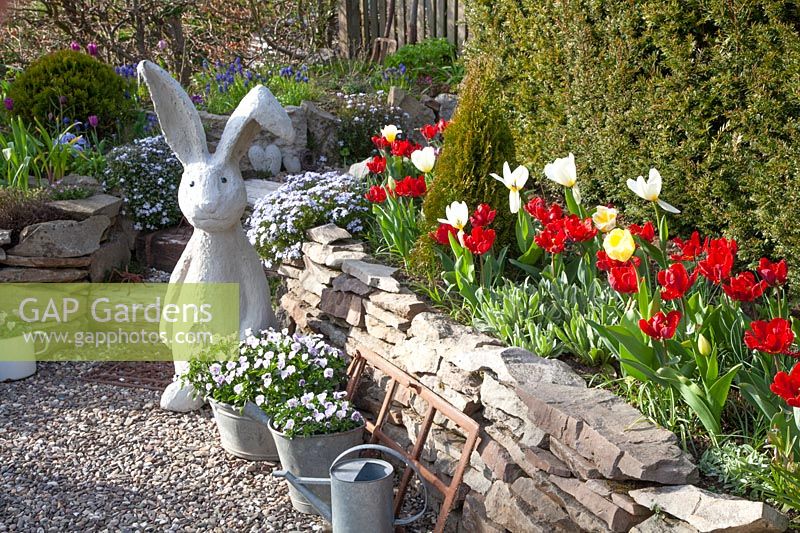Rock garden in spring with concrete rabbit sculpture 