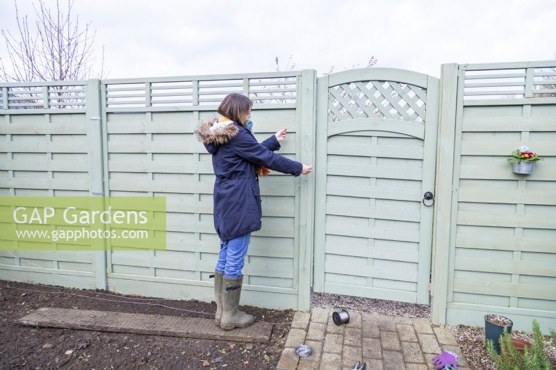 Woman feeding wire across the fence through the eyelets