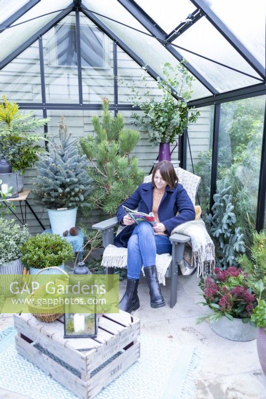 Woman reading magazine inside decorated greenhouse