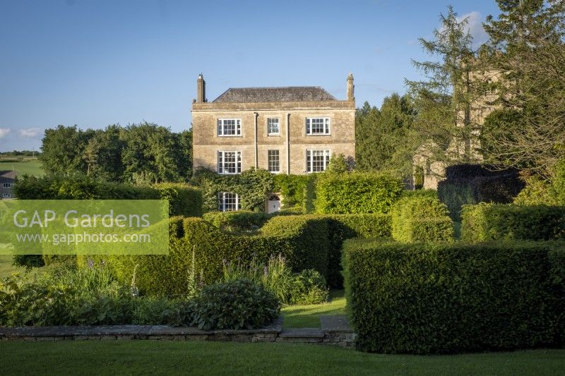 View of Daglingworth House, Gloucestershire, surrounded by formal yew topiary hedging