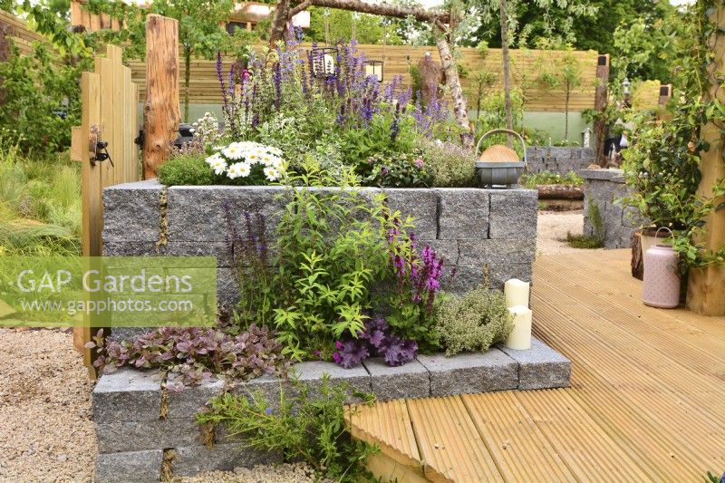 Raised bed, made of Connemara decorative wall system, near wooden decking. Planted with Thymus vulgaris,  Astilbe, Gillenia trifoliata, Leucanthemum superbum, Salvia Nemorosa, Thymus vulgaris, June
Designer: Mary Anne Farenden. Bord Bia Bloom, Super Garden, Dublin, Ireland.  


