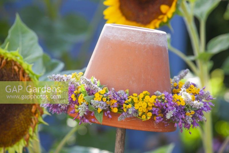 Upturned flower pot with a wreath of summer flowers including Allium, Agastache and Tanacetum vulgare.