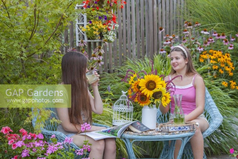 The girls hang out drinking and reading magazines on the terrace.