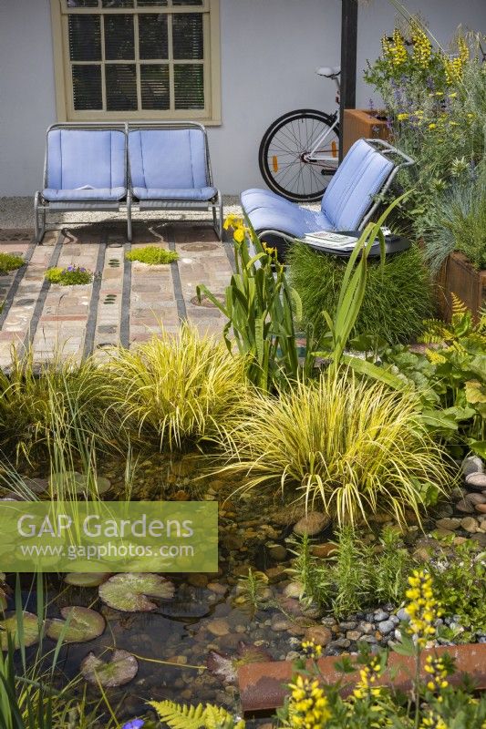 Urban front garden with a storage pond and seating area. Recycled seats from an old model Citroen car placed on a mosaic surface made from various reclaimed natural materials. Designer: Nicola Haines, Citroen Power of One at Bord Bia Bloom Dublin 2023