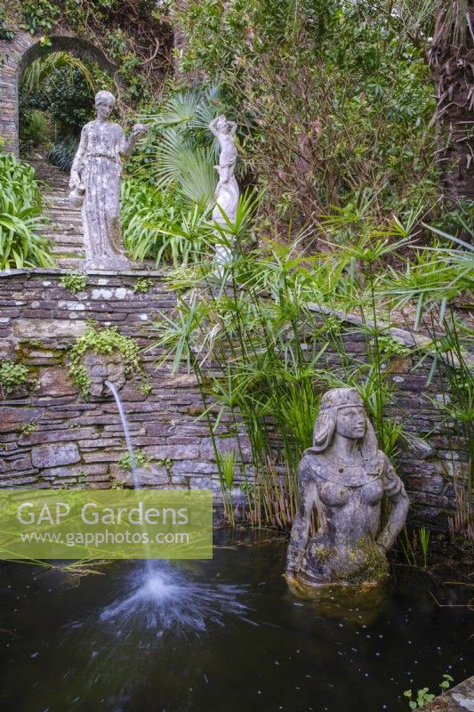 Egyptian statue of Cleopatra in quiet pond with Papyrus water plants