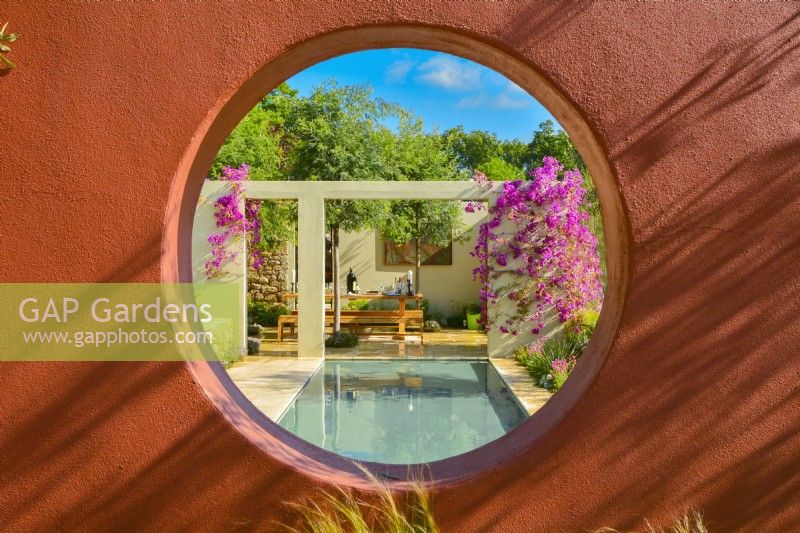 A orange compartment wall with circular open window with view to patio in Mediterranean garden. June
Designer - Alan Rudden