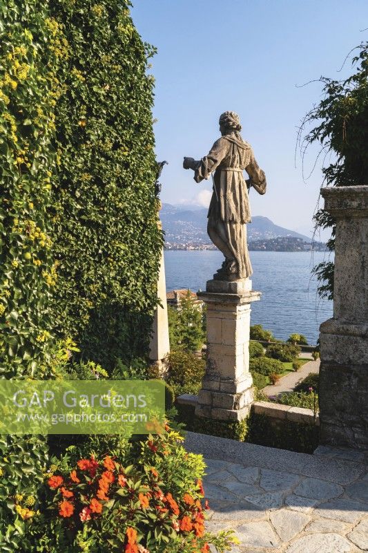 Part of the structure of Teatro Massimo in the Italian-style formal baroque Garden Isola Bella with a statue and view to Lago Maggiore.