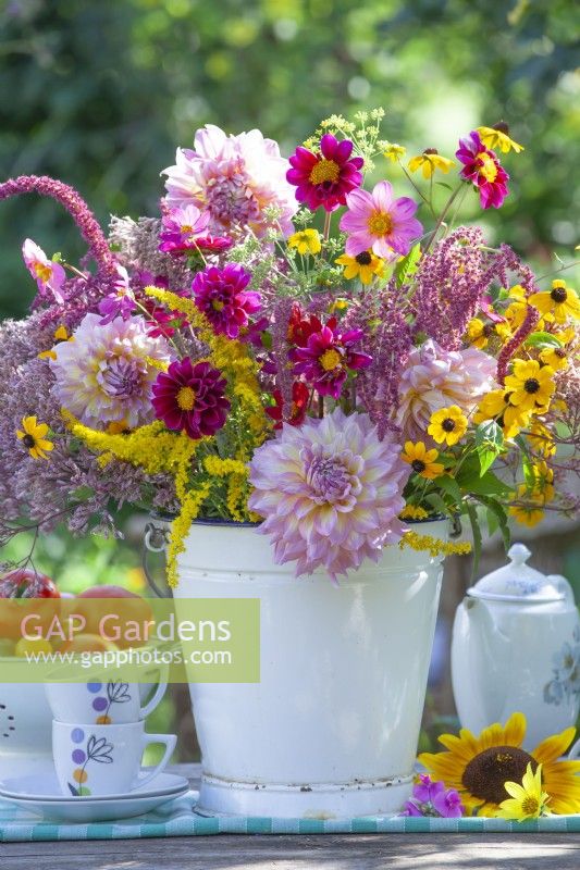 Bouquet of summer flowers including dahlia, cosmos, rudbeckia and amaranthus in enamel bucket.