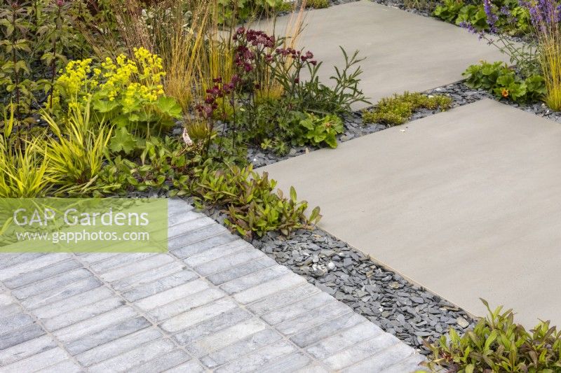 Limestone and porcelain setts and paving is separated by slate chippings and softened by planting.