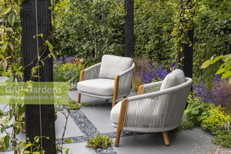 Seating area on a porcelain and slate paved area under a wooden pergola - Eco Oasis Garden - designer Dan Hartley - BBC Gardeners' World 2024
