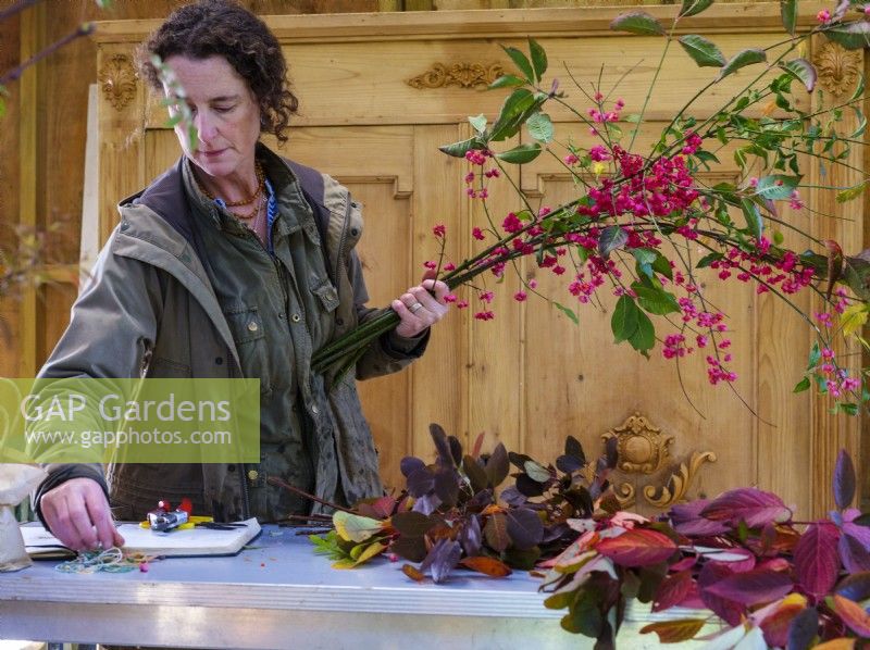Interior barn workshop where specialist foliage florist, Zanna Hoskins works with Autumn fruits and leaves gathered from her garden for use in seasonal arrangements. November, Autumn, Dorset, UK.