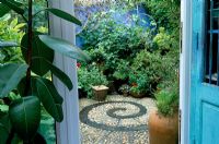 Patio - circular mosaic pattern. Viev from kitchen to containers and painted blue wall. Chesham St in Brighton Sussex