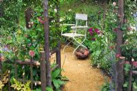 View to chair through arch in cottage garden. 'Fittleworth' by Fittleworth Horticultural Society. Chelsea FS 2005