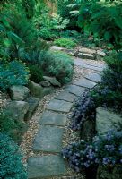 Path of stepping stones in gravel with rocks and borders with subtropical exotic planting