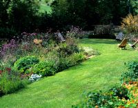 Informal country garden with mmixed borders,lawn and wooden seats