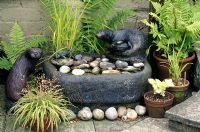 Stone sink used as a water feature with otter statues