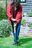Woman aerating lawn with garden fork