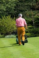 Man mowing the lawn with a petrol cylinder mower