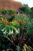 Exotic summer border with Phormium 'Sundowner', Brugmansia suaviolens, Dahlia 'Chiltern Amber', Eucalyptus gunnii and Vebena bonariensis at Great Dixter, Sussex