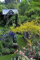 Small garden with dovecote. Planting includes Robinia, Roses and Delphinium