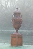 Terracotta urn with cobwebs in fog and frost