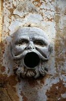 Open-mouthed stone face of man on wall used for extinguishing flaming torches - Villa Palagonia, Palermo, Sicily 