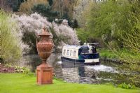 Terracotta urn by the canal with barge passing