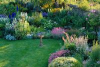 Border beside pond with lawn and sundial, planted with Hebe rakaiensis, Phuopsis stylosa, Verbascum and Lychnis flos-jovis - Oxfordshire