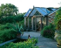 View of deck with pool, Agave americana in container and garden room behind - The Fovant Hut, Wiltshire
