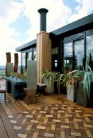 African themed roof terrace with iroko decking with inset herringbone design panels in coloured wood, zinc-wrapped table and stainless steel throne chairs