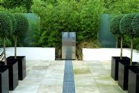 Small contemporary paved urban garden with stainless steel water feature and rill Designer Paul Dracott
