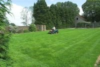 Boy on ride on mower in French walled garden