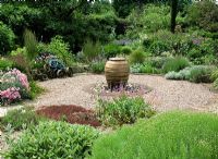 Dry gravel garden with urn water feature. Santolina neopolitana, Stachys byzantina and Grasses
