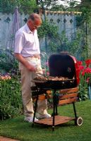 Man cooking food on barbecue in garden