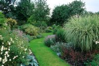 Summer double borders with lawn path running through centre at Glen Chantry, Wickham Bishops, Essex.