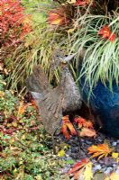 Chicken imported from Africa and made from scrap metal peers up at a blue glazed container planted with grasses for autumn effect. 