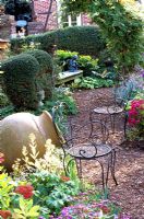 Mulch path with two ornate garden seats and ornaments
