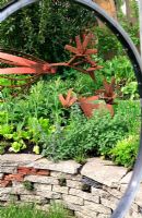 Garden built from recycled materials - Windows made from bicycle wheels, chicken sculptures made from old mower parts and underplanted with vegetables and herbs
