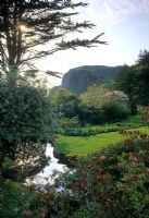 Stream beside lawn in garden with mountain in background - An Cala, Dumfries, Scotland

