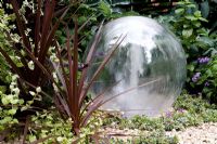 Glass ball water feature with phormium. The Way Forward, Design - Zoe Cain, Jim Buttress VMH and Jocelyn Armitage, Sponsor - St Joseph's Hospice and Perennial(Gardeners' Royal Benevolent Fund)
