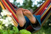 Boy relaxing in a colourful striped hammock, hung from trees.  May