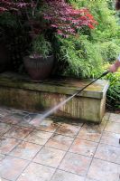 Pressure washing tiled patio garden to remove moss and algae