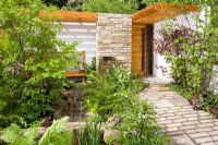 Sunny front garden with slatted roof over wooden bench and porch. Planting includes Acer palmatum cultivars, ferns, Irises and Corylus - Tokyo City Garden, Chelsea Flower show 2008
