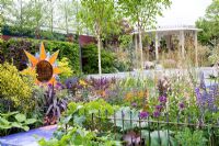 Mosaic sun surrounded by mixed colourful planting of Phormium, Euphorbia, Digitalis, Anthriscus sylvestris 'Ravenswing', Allium and Iris - From Life to Life, A Garden for George, RHS Chelsea Flower Show 2008
