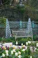The sunken garden in Spring with Tulips, wooden tripods and wooden bench - Holker Hall, Cumbria