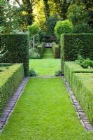 Grass paths and evergreen hedges in formal country garden