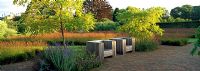 Seating area in the Drifts of Grasses Garden planted with Molinia caerulea subsp. Caerulea within the walled Garden at Scampton designed by Piet Oudolf