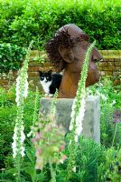 Fangle the family cat on sculpture by Paul Richardshon with Digitalis in foreground