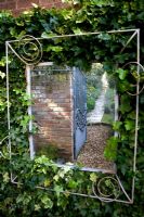 Mirror on Ivy covered wall, reflecting a pathway to increase the size of a small urban garden 